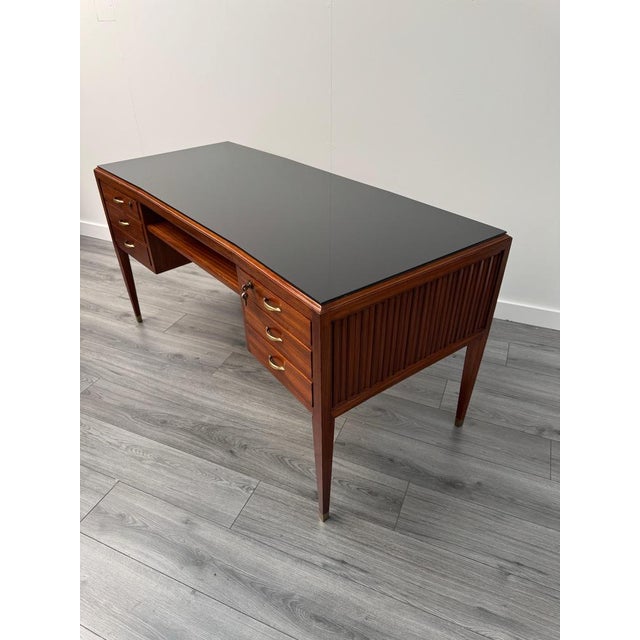 A stunning semi curved writing desk featuring three lockable drawers with brass handles on each side with a deep shelf to...