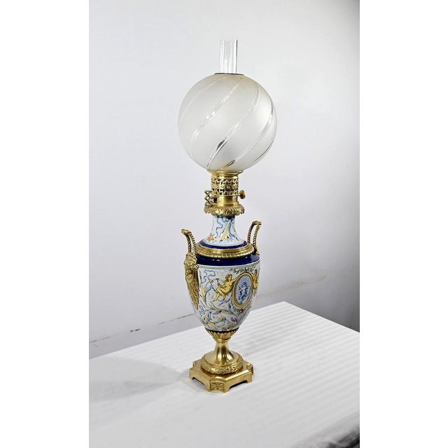 Polychrome earthenware oil lamp, adorned with bronze and fitted with a globe engraved with curved furrows. A large bronze...