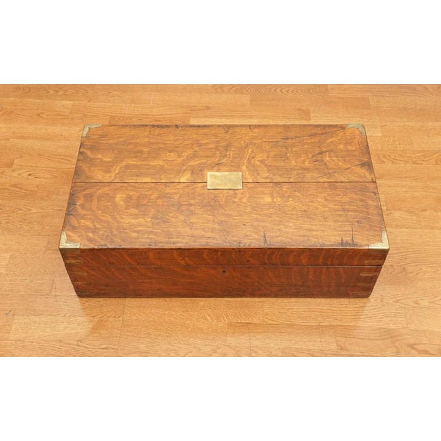Made of solid oak with brass corner braces in the 1840-1850's, guards and center plate detail, this antique storage box is...