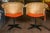 Pair of black iron swivel chairs with protectively wrapped rattan backs and orange vinyl seats. Seat height is 17.5".
