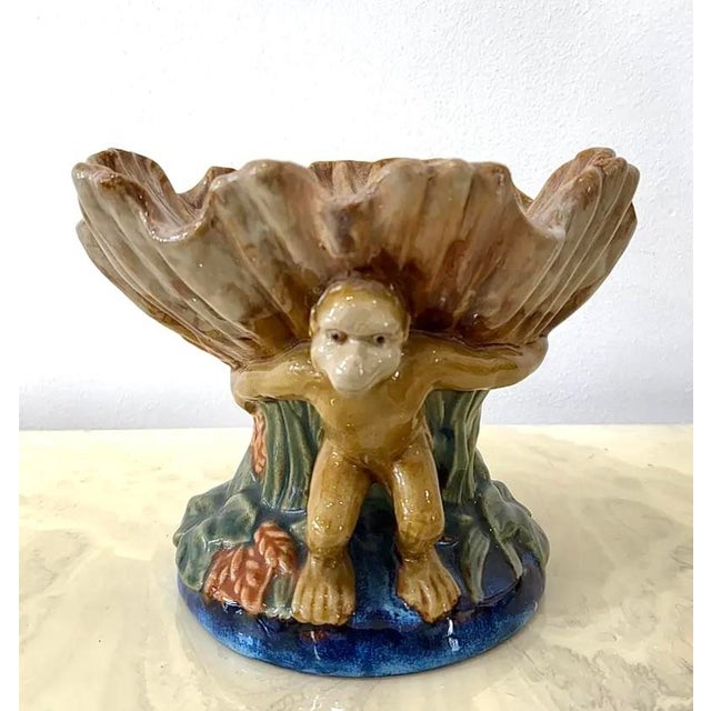 Wild and whimsical, this vintage ceramic bowl features three sculpted monkeys supporting a large shell-shaped basin on...
