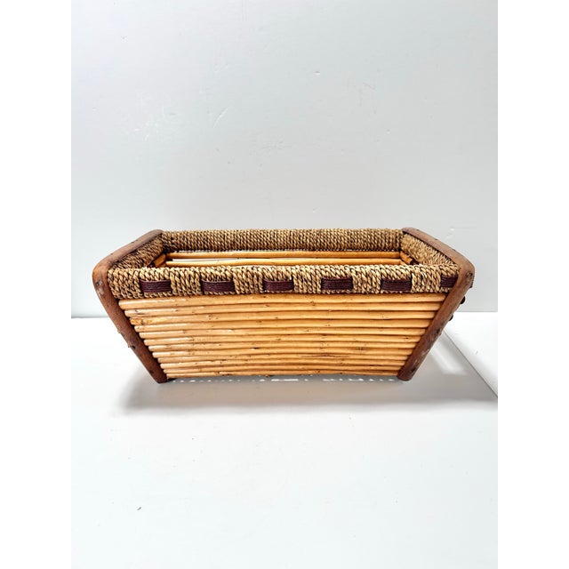 A beautifully constructed vintage rattan and handwoven reed basket featuring a structured rectangular form with sculptural...