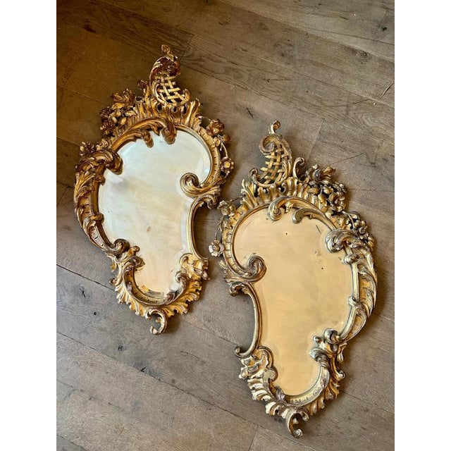 A pair of Italian carved giltwood Rococo mirrors. Reataining the original bevelled plate glass with some foxing. Warm...