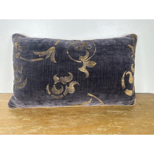 An elegant decorative pillow crafted from luxurious stenciled velvet by Nomi, featuring softly scrolling motifs in warm...