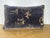 An elegant decorative pillow crafted from luxurious stenciled velvet by Nomi, featuring softly scrolling motifs in warm...