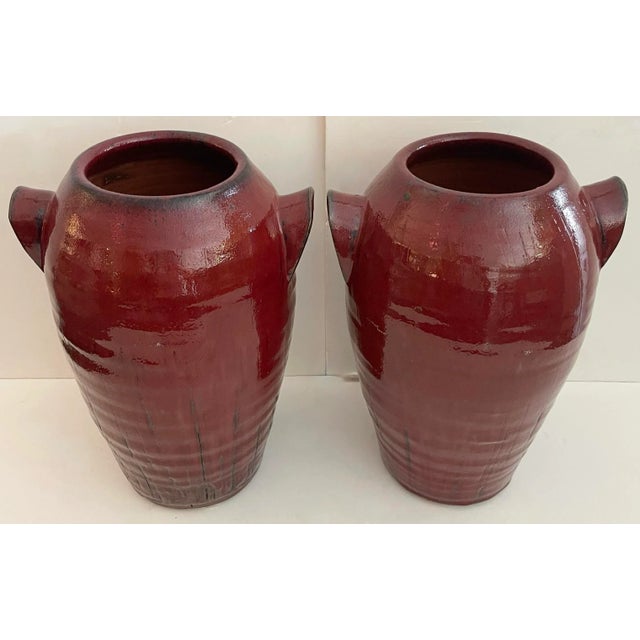 Interesting and very good quality pair of handmade pottery urns. Very heavy and exquisitely finished. Glossy red with...