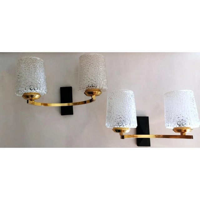 Three wall sconces with a refined and pleasant design; the structure of each one, made of brushed and polished brass, is...