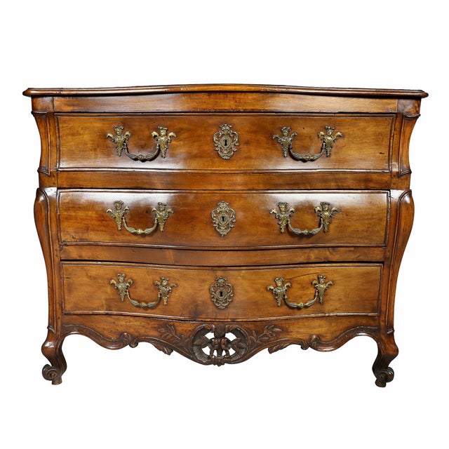 With serpentine top over three drawers with original handles and a carved floral pierced apron raised on carved scrolled...