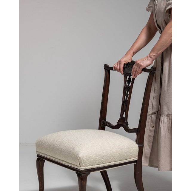A side chair whose dark mahogany carved back, cream upholstered seat gives it real character at first glance. It was made...