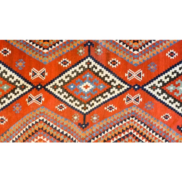 A beautiful mid-20th century Persian Harsin Kilim rug with three large diamond medallions each with a geometric flowers in...