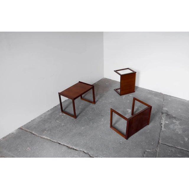 Set of three nesting tables by Punch Design Inc., rectangular sled legs rise slightly above the tabletop, forming a small...
