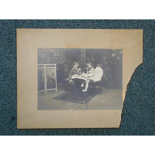 This vintage silver gelatin photograph depicts a very young boy and girl playing "dress-up" in adult clothing. They appear...