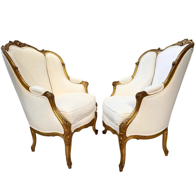 A beautiful pair of French Louis XV style gold gilt bergères with finely carved opposing C-scrolls on the crests,...