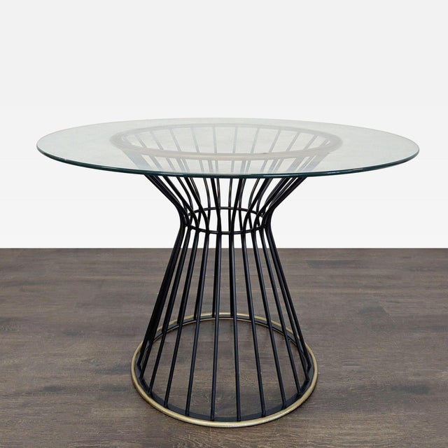 This Pottery Barn dining set features a sleek round glass table with a sturdy black metal wire base and brass accents. The...