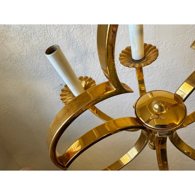 Vintage brass chandelier with a Fleur-de-lis inspired open-frame design. It has four arms candle style light holders with...