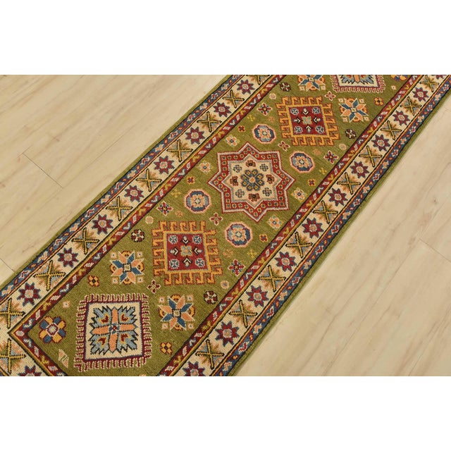 A tribal Caucasian Kazak runner hand-knotted with fine wool on a cotton foundation. This rug features a row of geometric...