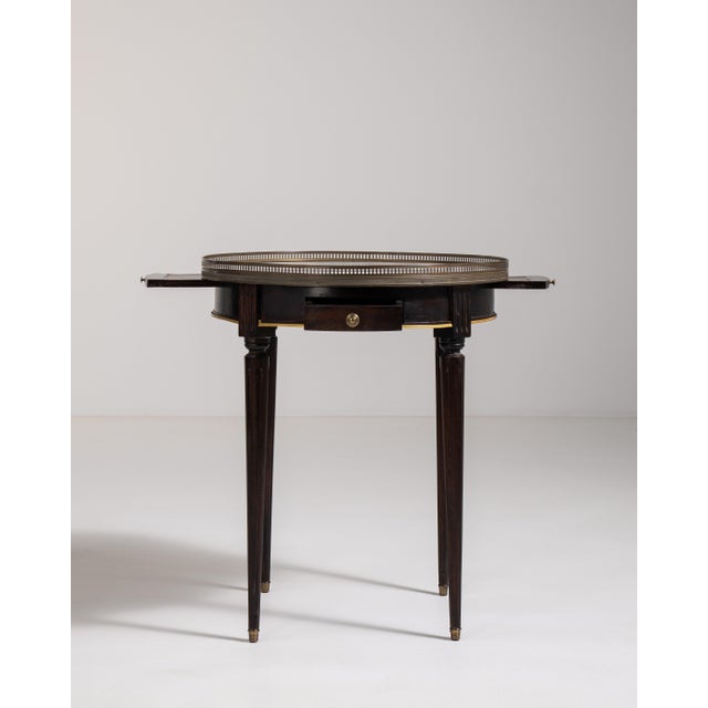 A classic French bouillotte table featuring a marble top and brass detailing. Traditionally used for gaming, the design...
