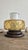 A distinctive mid-century table lamp featuring a rounded amber glass body, a frosted white glass upper element, and a...