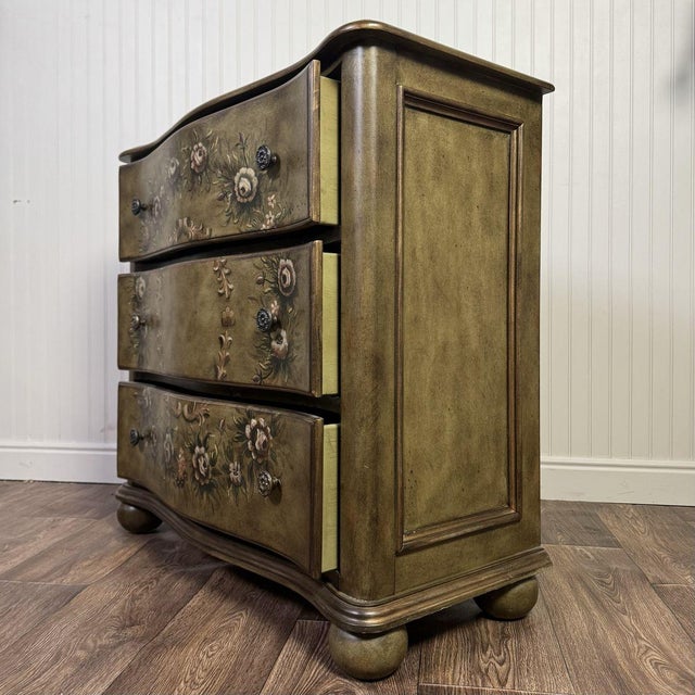 Vintage Lane serpentine chest of drawers with hand-painted florals over a soft green finish. Three curved drawers are...