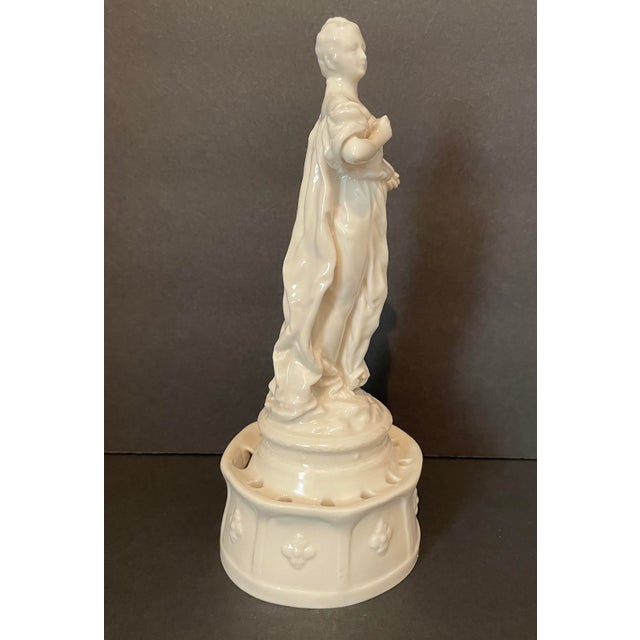 Antique porcelain figure of an artist, possibly a muse, standing with a pallette and paint brush. She is in a robe on a...
