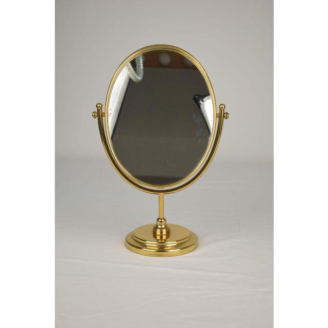 An elegant Italian table mirror dating back to the 1970s. Crafted from brass with a gold finish, it features a simple,...
