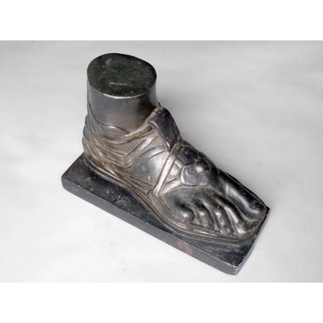 Early 20th century cast iron trade stimulator with cast iron foot with gladiator sandals.