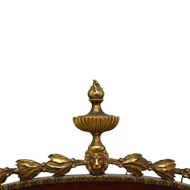 An oversized antique French oval wall mirror, dating to approximately 1880. The mirror features a carved gilt wood frame...