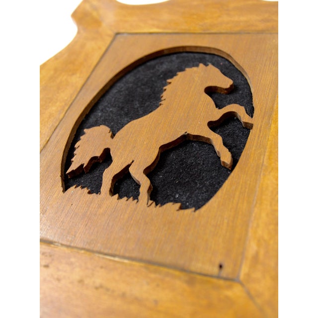 This vintage wooden wall plaque features a rearing horse silhouette set within an oval opening and framed by a softly...