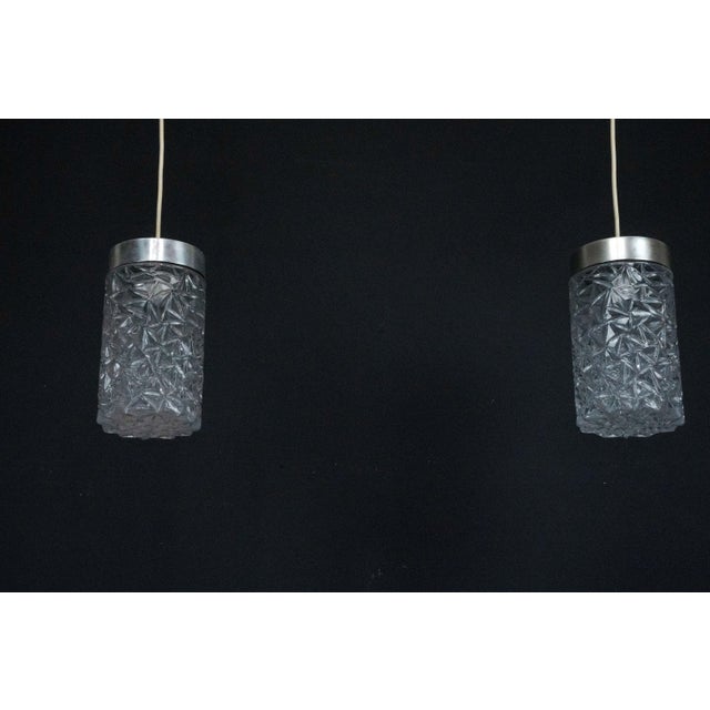 Elegant pair of Italian pendant lights dating from the 1970s, featuring textured glass shades paired with polished...