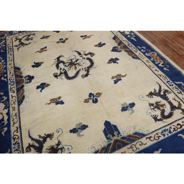 An early 20th century Chinese Peking Dragon motif rug with a spacious open field design on an ivory ground Measures: 7'3''...