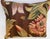 An exquisite antique-style pillow upholstered in richly woven 19th-century tapestry, set against a deep warm brown ground...