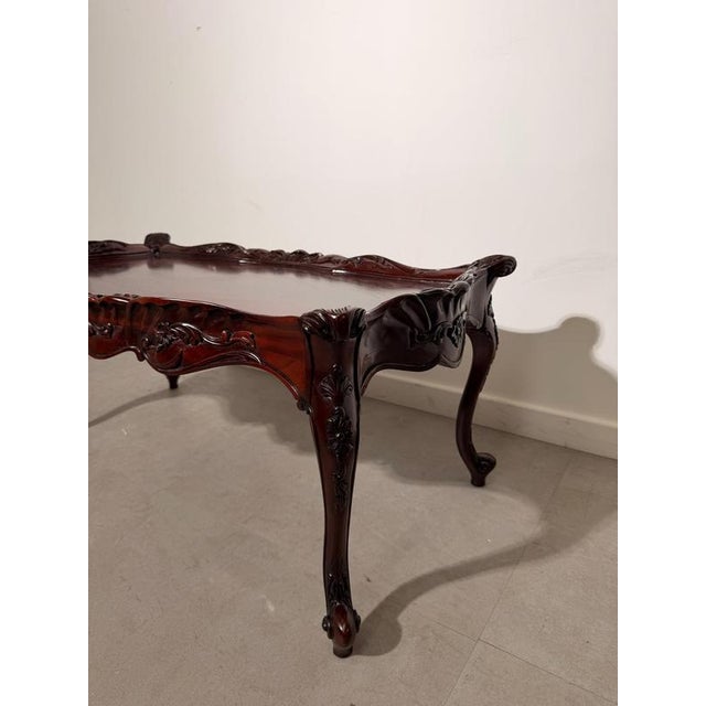 A Rococo Revival coffee table in a rich mahogany-toned finish, featuring elaborate carved decoration throughout. The table...