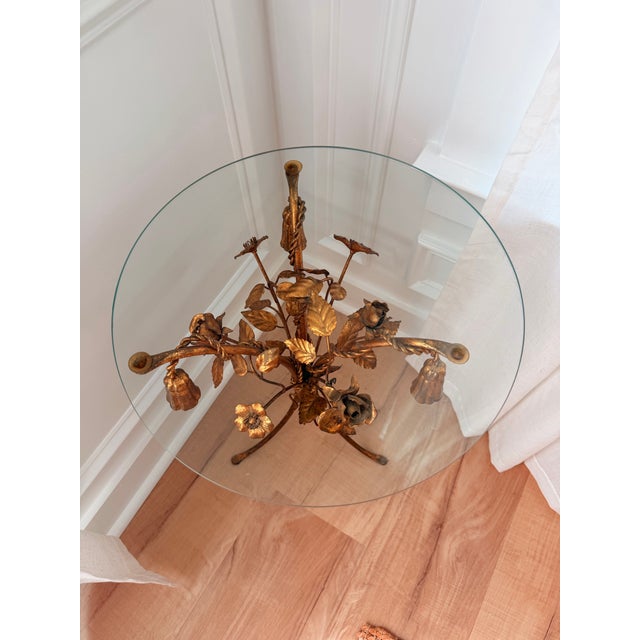 Delightful vintage Hollywood Regency side table featuring an ornate gilt tole floral base with sculptural hand-formed...