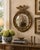A Federal-style giltwood convex mirror crowned with a carved eagle, its wings outstretched above a laurel motif—an...