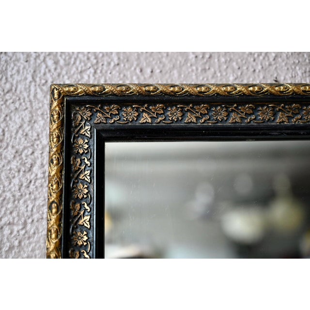 Simple yet charming, this wall mirror evokes the understated elegance of the early 1900s. Its blackened wood frame is...