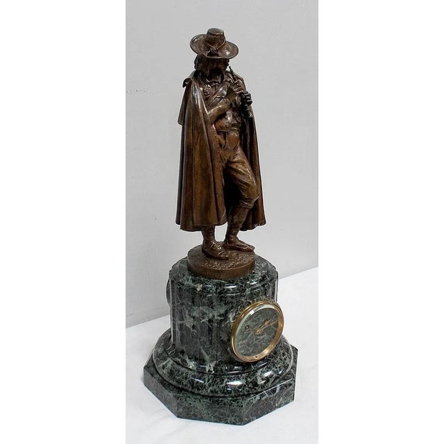 Clock composed of a Bronze Sculpture with Brown Patina representing a Flute Player, surmounting a Green Marble Base of Sea...