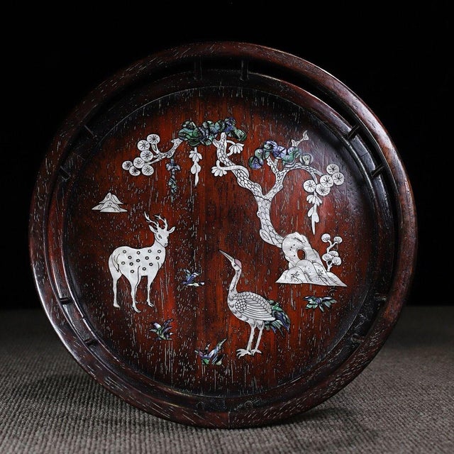 A beautifully crafted Chinese round tray or display stand, made of dark Zitan wood. The tray is enclosed by a low,...