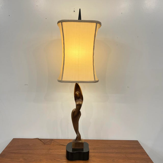 Heifetz mid century modern lamp with carved wooden figure. Signature on lamp base. Lamp shade dimensions 12.25”w x 10.25”d...