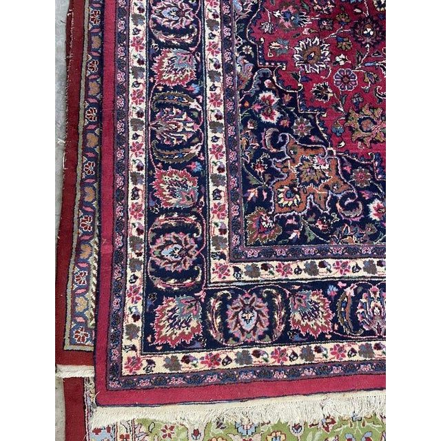 A quality hand-knotted Kashan rug featuring a dark, vibrant red and blue palette, a conforming border, and a classic...