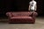 Classic burgundy leather Chesterfield sofa with deep tufting and nailhead trim. This piece features full-grain leather...