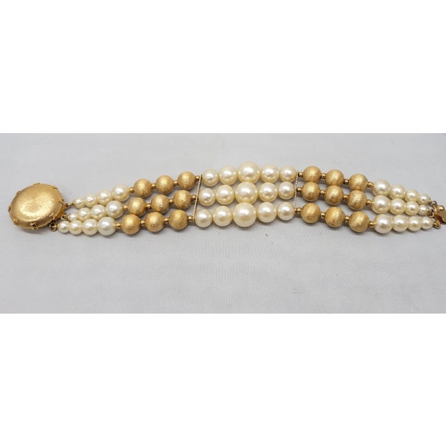 This is part of Chairish’s Costume Jewelry assortment. 1950s brushed goldtone 3-strand beaded faux-pearl and goldtone bead...