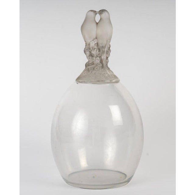 "Dove-like" vase, in molded pressed glass, the lid decorated with a pair of intertwined lovebirds. Signed René Lalique...