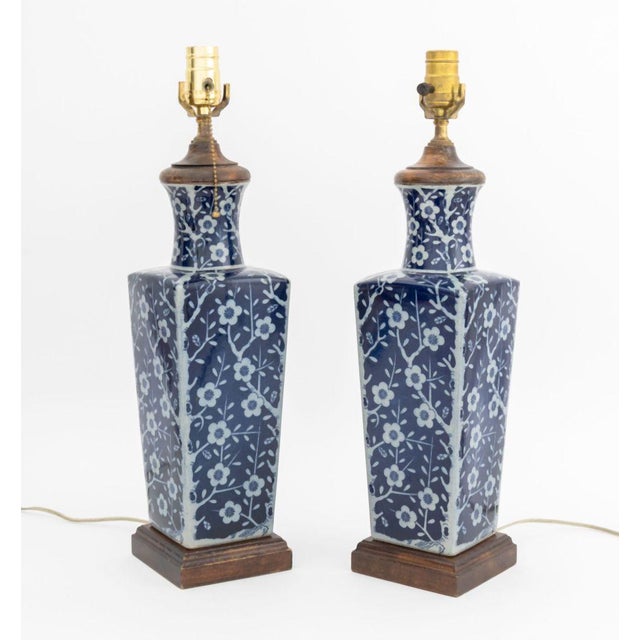 Pair of Chinese Blue and White Ceramic Vases Mounted as Lamps, with floral design on carved wood bases. 20.5" H x 5" W x...