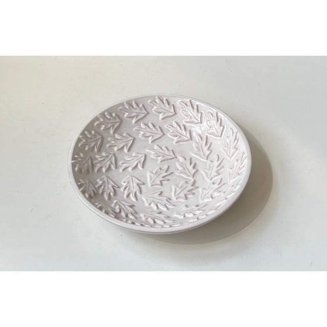A stylish white glazed dish or centerpiece bowl decorated with oak leaves in relief. Hand-made by the danish ceramist...