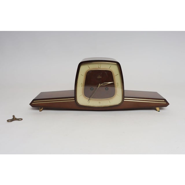 Classic Art Deco mahogany mantle clock with dramatic splayed brass legs by Emes (ca. 1930s, Germany). Sleek and...
