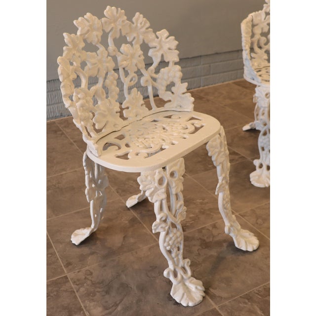 A substantial five-piece American cast iron garden suite featuring an elaborate grapevine pattern, comprising a curved...