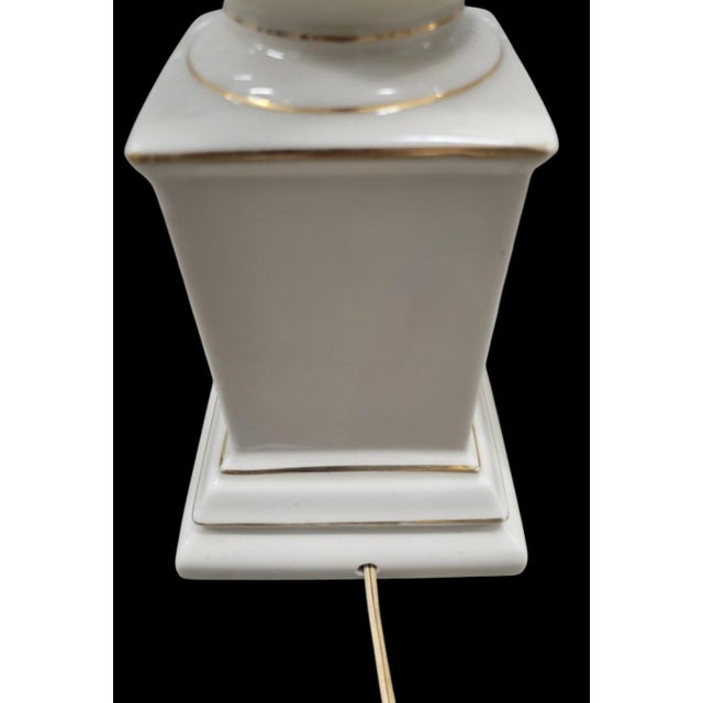 A beautiful pair of slightly off white and gold trim Traditional table lamps in the style of Lenox. The lamps are made of...