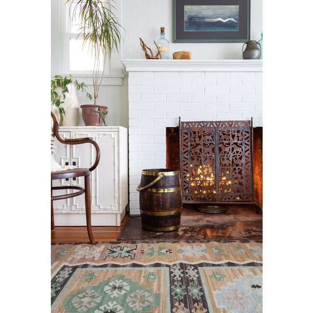 This antique Dutch wooden cooper barrel is composed of wooden staves, brass hoops, and an articulated brass handle. A...