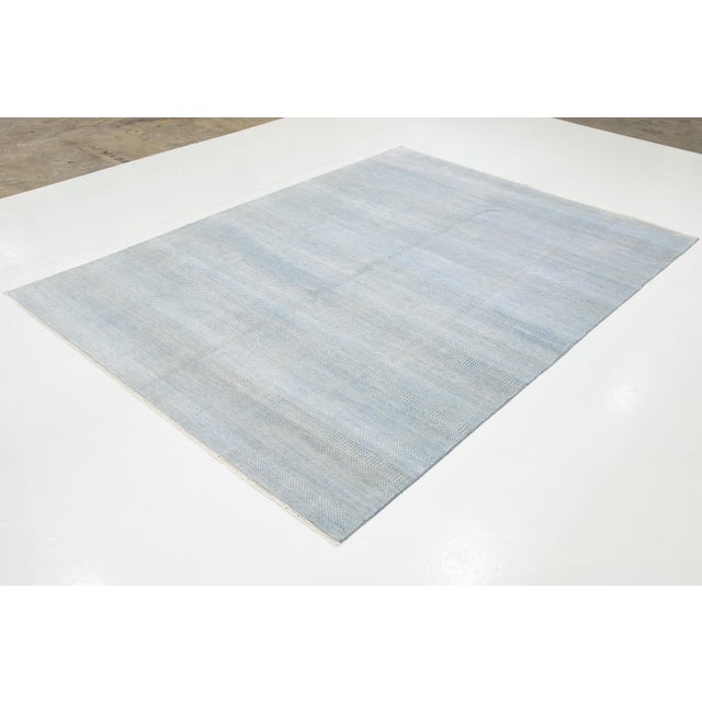 This beautiful rug features a contemporary gray design, handknotted with care, showcasing a charming light blue geometric...