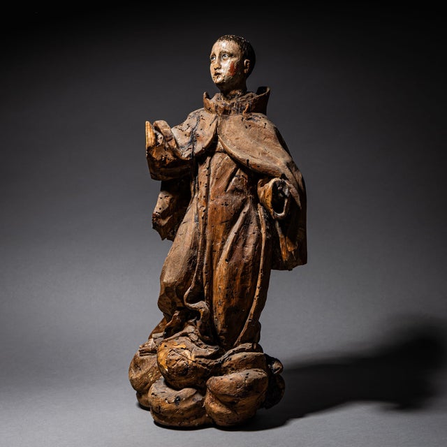 Carved and partially polychromed wooden sculpture of a Franciscan monk with raised arms and an upward gaze, likely...